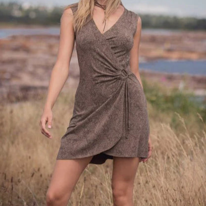 Woman in a brown dress standing in a field with a blurred natural background